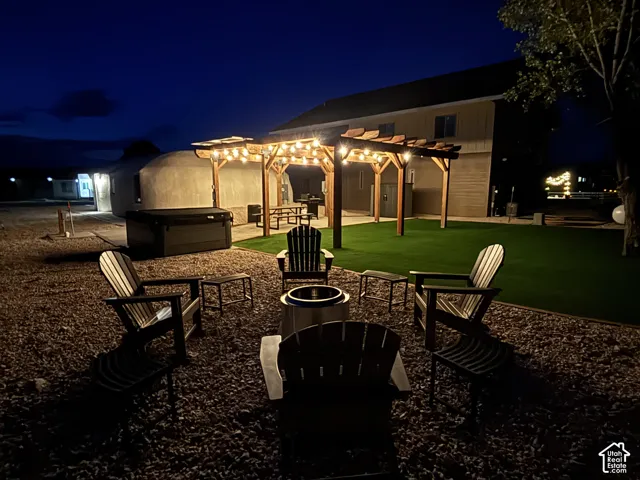 Outdoor living space featuring a wood pergola, synthetic lawn, gravel grounds, and a hot tub