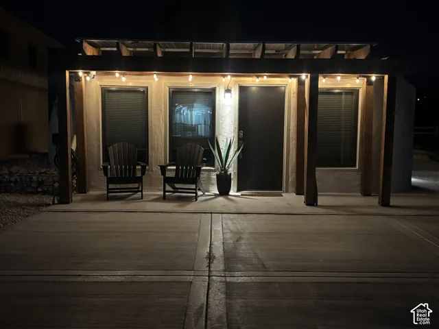 Exterior featuring a concrete patio, a wooden pergola with integrated solar panels, and stucco siding