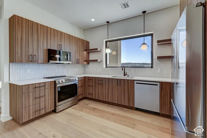 Kitchen featuring horizontal-grain wood cabinetry, quartz countertops, vertical tile backsplash, stainless steel appliances, and wood-finish flooring