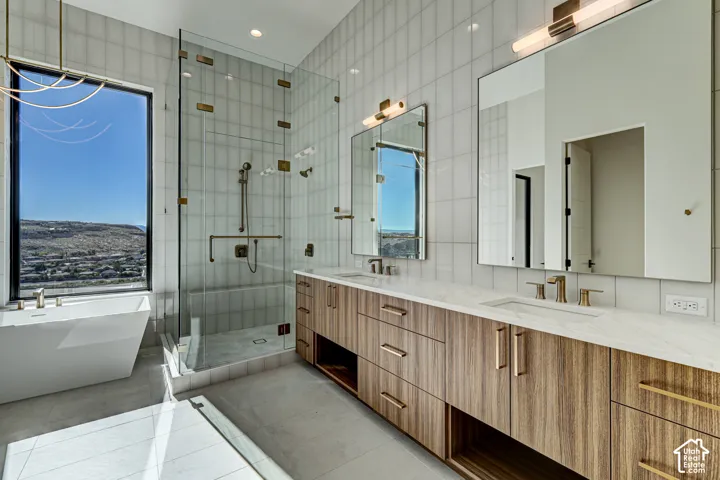 Double vanity with wood-finish cabinetry, solid-surface countertop, rectangular undermount sinks, and metallic hardware
