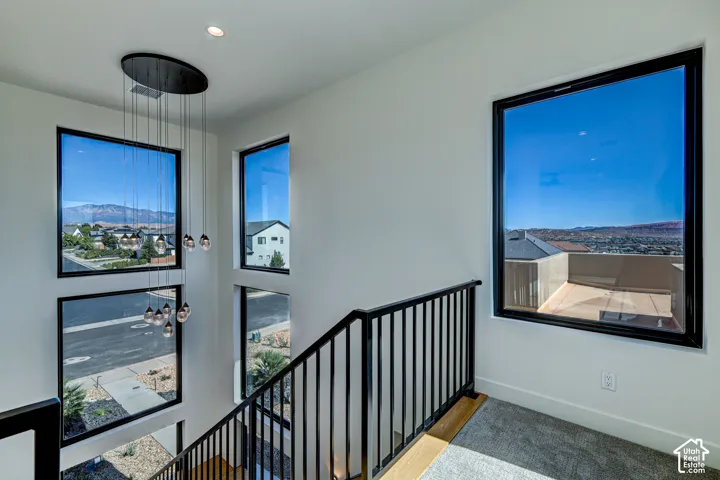 Multi-story space featuring expansive picture windows with black frames, a suspended multi-pendant light fixture, and black metal handrailing