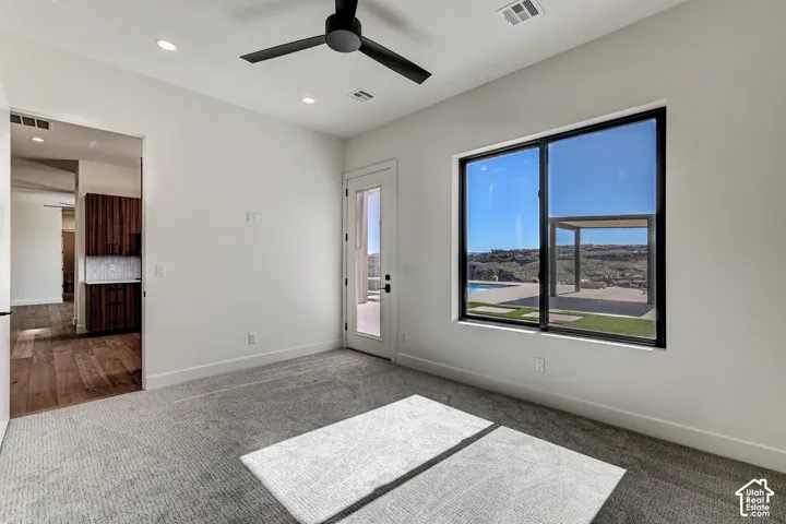 Room featuring neutral carpeting, recessed lighting, a modern ceiling fan, and large windows with black framing
