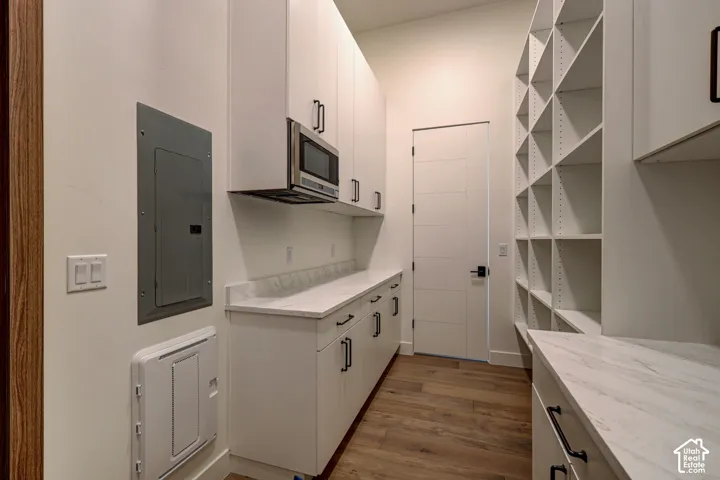 Custom white cabinetry, built-in open shelving, stone-finish countertops, matte black hardware, and wood-finish flooring