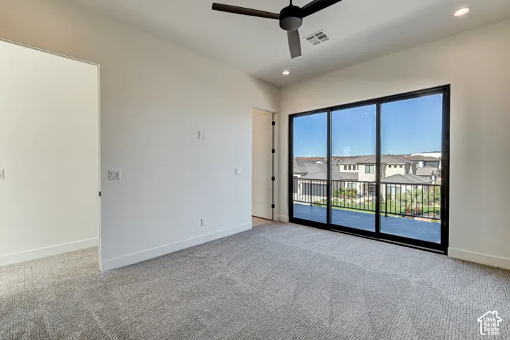 Large black-framed sliding glass doors, carpeted flooring, matte black ceiling fan, and recessed lighting