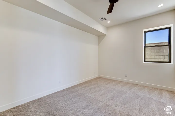 Neutral-toned carpeting, recessed ceiling lighting, a dark-finish ceiling fan, and a single-hung window with a dark frame