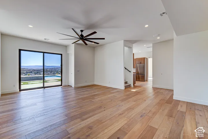 Open-concept interior featuring wood-finish flooring, recessed lighting, a modern multi-blade ceiling fan, and a large sliding glass door with a pool and mountain backdrop