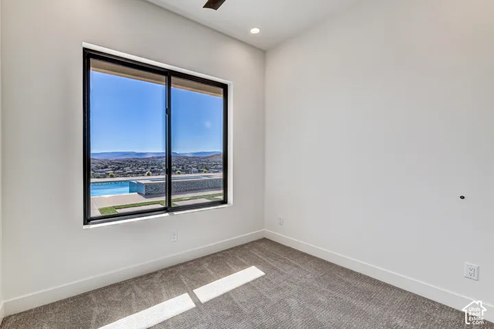 Interior room featuring high ceilings, wall-to-wall carpeting, recessed lighting, ceiling fan, and a large picture window with mountain and pool scenery