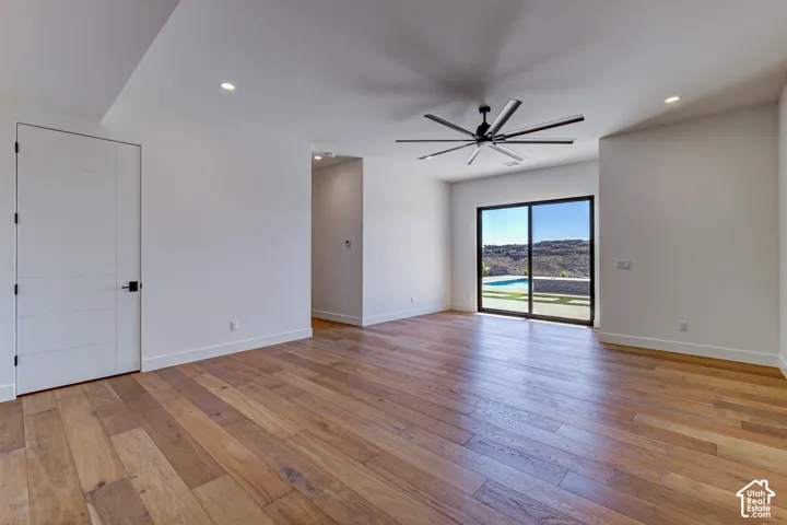 Modern interior featuring wide-plank wood-finish flooring, recessed lighting, a multi-blade ceiling fan, and sliding glass doors