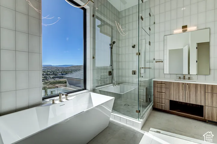 Primary Bathroom. Freestanding soaking tub, European glass door walk-in shower with tile surround, wood-finish vanity with countertop basin, and floor-to-ceiling window