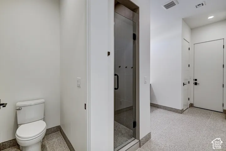 Bathroom featuring large-format tile flooring, a glass-enclosed shower, a wall-mounted toilet, recessed lighting, and matte black hardware