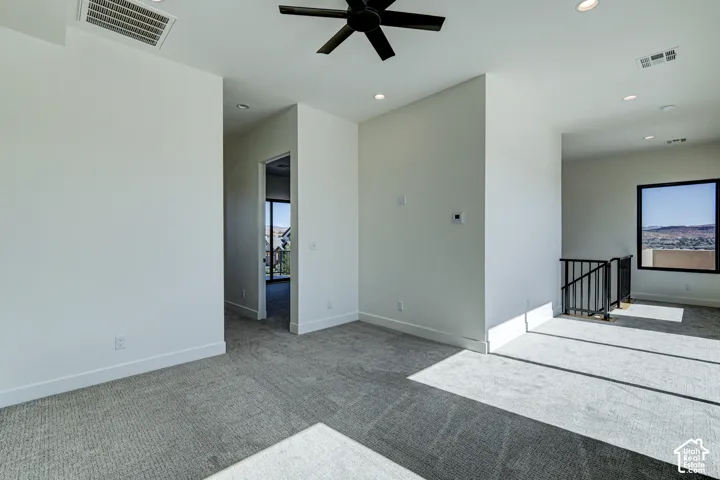 Interior space featuring carpeted flooring, recessed lighting, a matte black ceiling fan, and a black metal stair railing