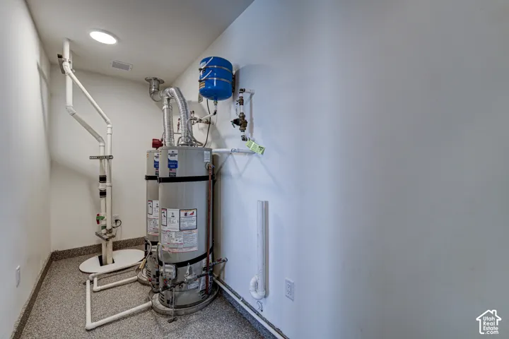 Dual water heater system featuring metallic cylindrical tanks, integrated pressure expansion tank, overhead recessed lighting, and epoxy-coated flooring