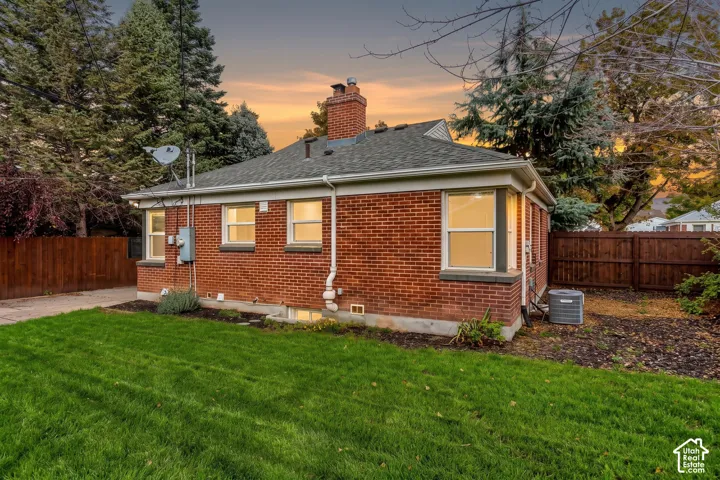 Exterior of red brick construction featuring a chimney, a lawn area, and a wood perimeter fence