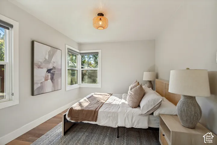 Neutral-toned interior space featuring wood-finish flooring, a multi-pane bay window, and a woven basket-style semi-flush mount light fixture