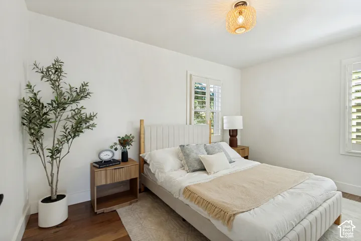 Neutral-toned interior featuring wood-finish flooring, plantation shutters, and a decorative woven-style ceiling light fixture