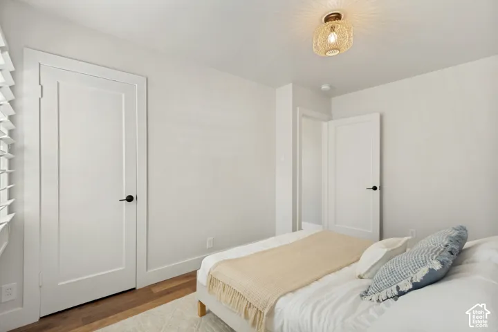 Room featuring wood-finish flooring, white shaker-style interior doors with matte black hardware, and an ornate, semi-flush mount drum light fixture