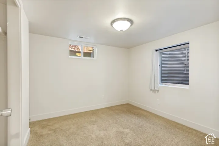 Neutral-toned wall-to-wall carpeting, crisp white interior paint, flush-mount ceiling light fixture, and two egress-style windows