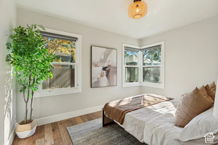 Neutral wall paint, wood-finish flooring, corner windows, and woven drum ceiling fixture