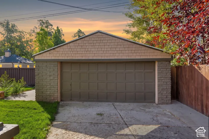 Detached garage featuring brick exterior walls, shingle-style siding, and a sectional door