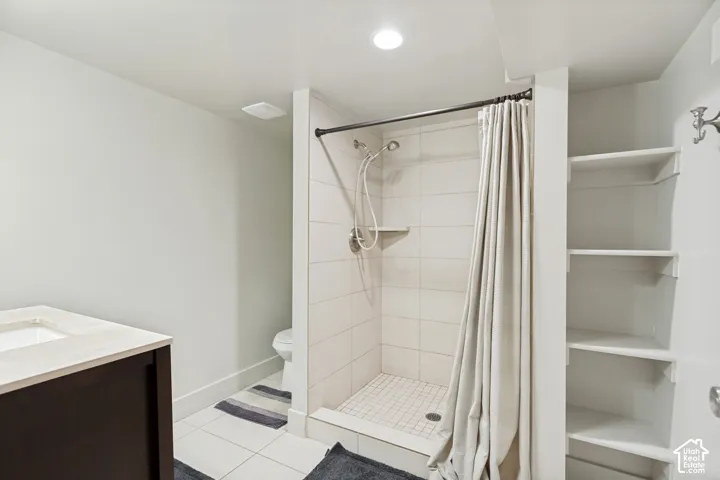 Walk-in shower with light-toned wall tile, built-in shelving, dark-finish cabinetry, and recessed lighting