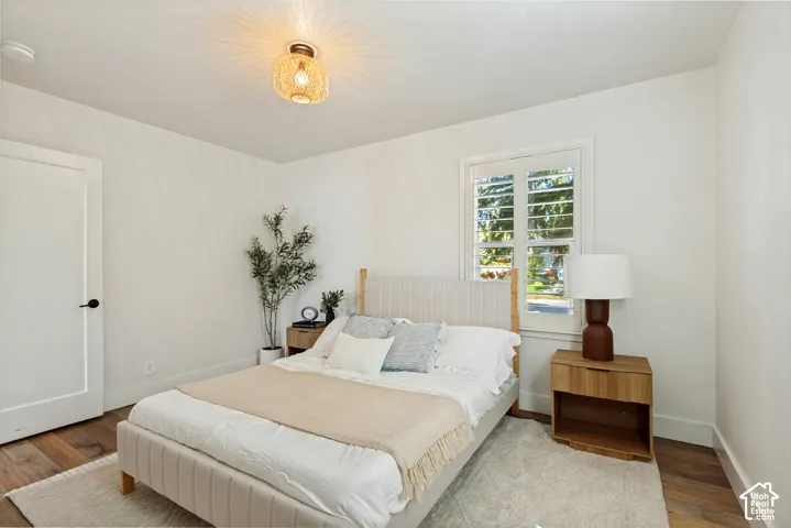 Interior space featuring wood-finish flooring, white plantation shutters, and a basket-weave flush mount light fixture