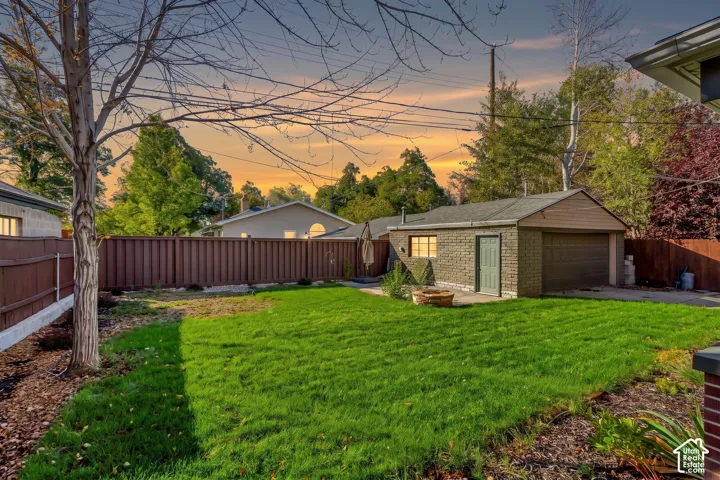 Private backyard featuring a manicured lawn, masonry-walled garage, stone fire pit, and full-height privacy fencing