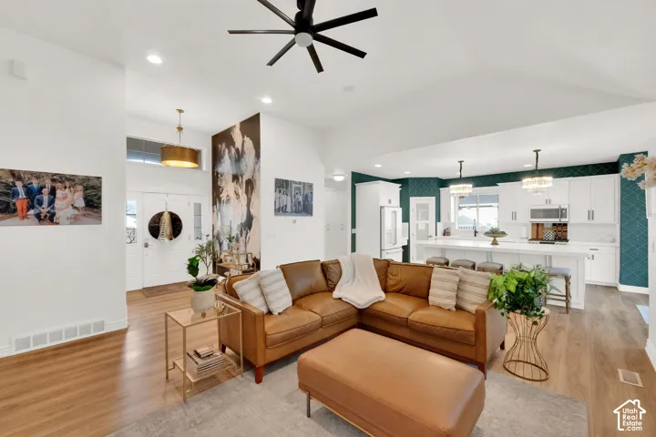 Open-concept interior featuring wood-finish flooring, vaulted ceilings, white cabinetry with a quartz island, geometric patterned wall accents, and recessed lighting