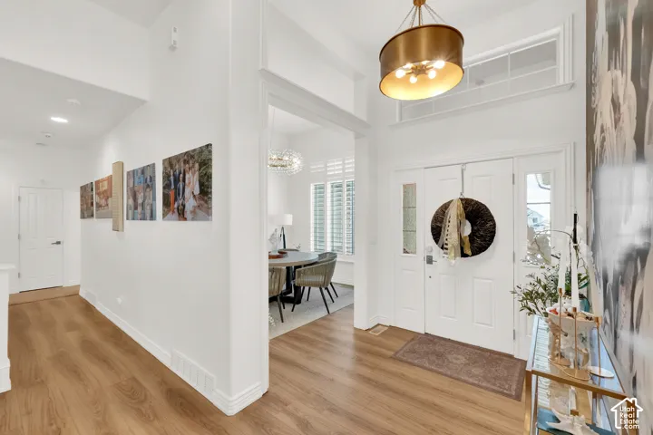 Entryway featuring high ceilings with an overhead transom window, wood-finish flooring, and a decorative drum-style pendant light fixture