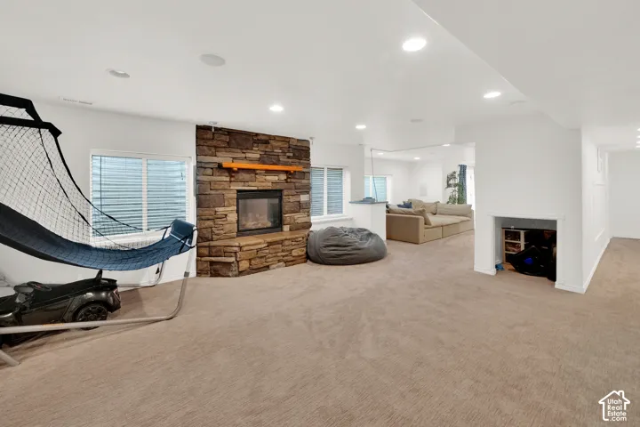 Stone-veneer fireplace with a wood mantel, recessed lighting, wall-to-wall carpeting, and a built-in recessed storage alcove
