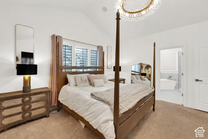 Vaulted ceiling, decorative chandelier, three-panel window with plantation shutters, neutral carpeting, and interior door leading to tiled bathroom space