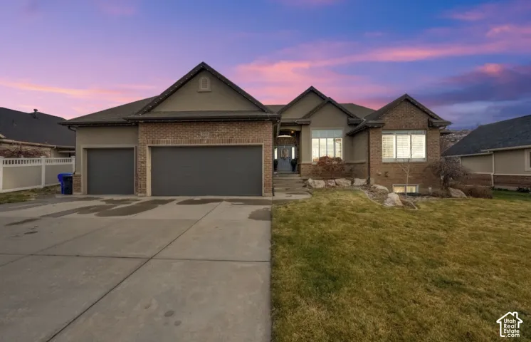 Brick and stucco exterior featuring a three-car garage, concrete driveway, and covered entryway