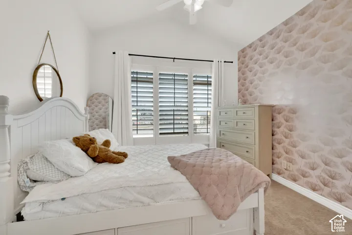 Vaulted ceiling featuring a central light fixture, accent wall with geometric pattern wallpaper, and triple-pane windows outfitted with adjustable shutters