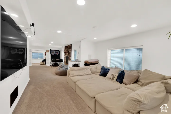 Spacious interior featuring a stone-clad fireplace, carpeted flooring, recessed lighting, and windows with horizontal blinds