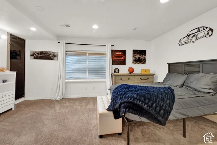 Neutral-toned carpeting, recessed ceiling lighting, and a window featuring horizontal blinds