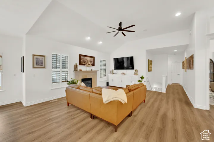 Vaulted ceilings, wood-finish flooring, central fireplace with mantle, plantation shutters, and recessed lighting