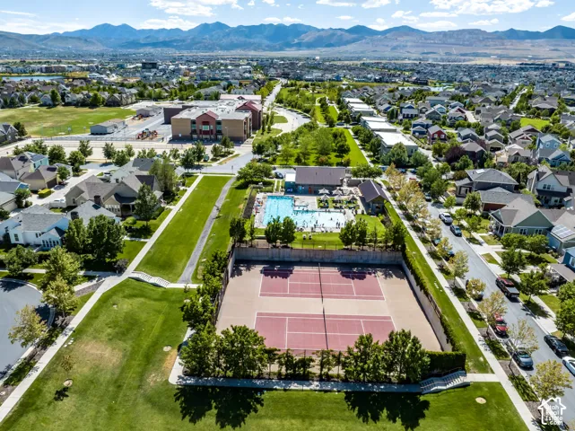 Aerial perspective featuring tennis courts, swimming pool, manicured lawns, and mountain backdrop