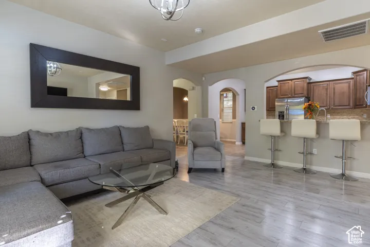 Wood-finish flooring, architectural archways, breakfast bar, and neutral wall tones