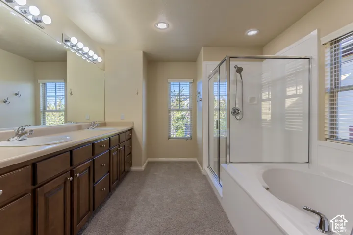 Double vanity with integrated sinks, wood cabinetry, walk-in glass shower enclosure, and separate soaking tub
