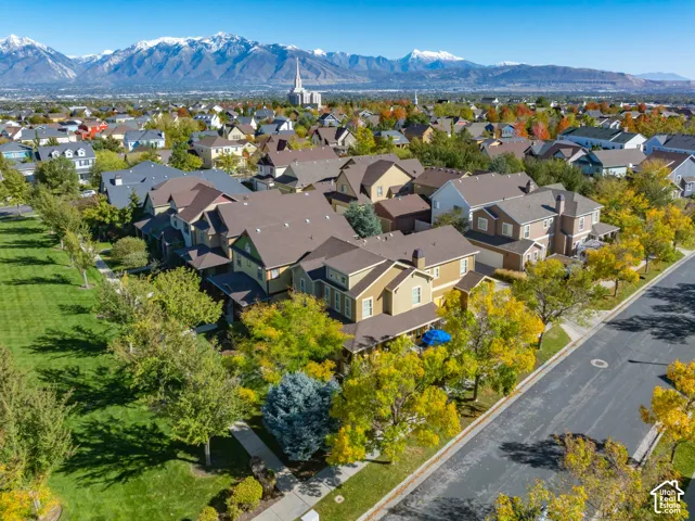 Aerial perspective featuring mountain backdrops, mature trees, manicured lawns, and asphalt streets