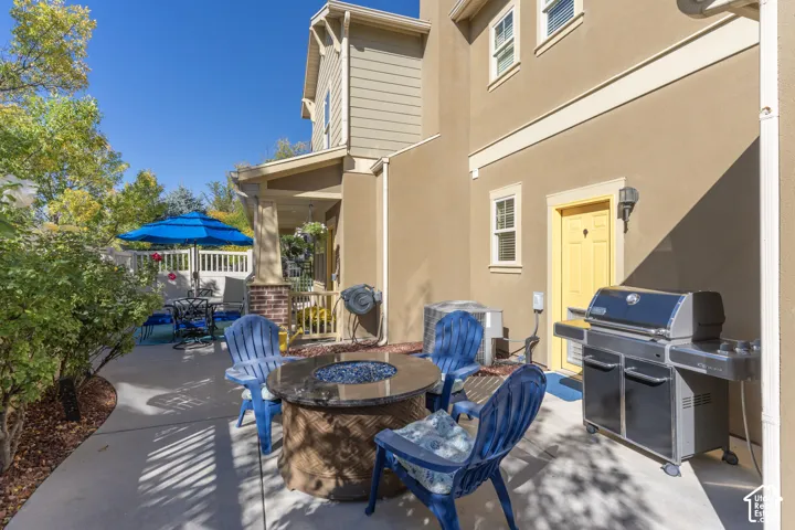 Concrete patio featuring a covered porch with brick-accented columns, exterior siding, and a rear door entry