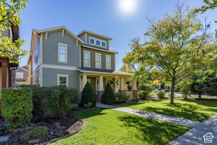 Two-story home with lap siding, a front-facing porch with decorative columns, brick masonry accents, and a landscaped front yard