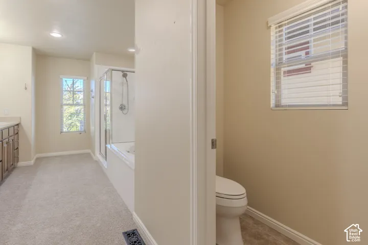Bathroom featuring a separate water closet, a glass-enclosed shower, a deep soaking tub, and custom wood-finish cabinetry with an integrated countertop
