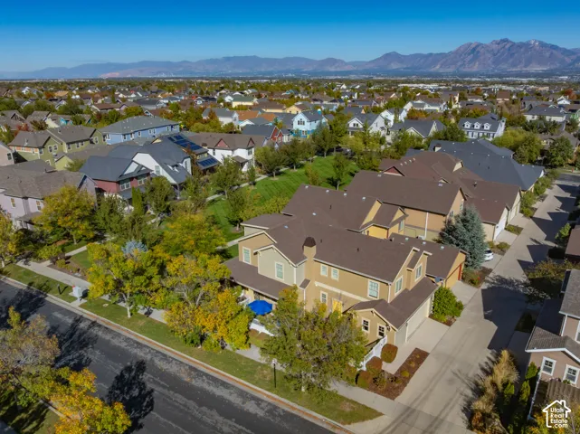 Aerial perspective featuring a multi-story residence with a multi-gabled roofline, attached multi-car garage, and mountain range backdrop