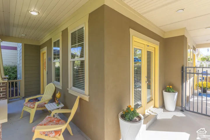 Covered porch featuring concrete flooring, recessed lighting, double glass-paneled entry doors, and paneled exterior siding