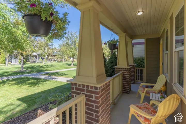 Covered front porch featuring tapered support columns, brick masonry bases, beadboard ceiling, and horizontal siding