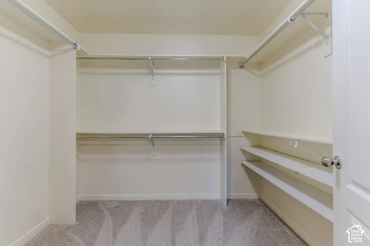Walk-in closet featuring tiered shelving, integrated metal hanging rods, and neutral carpeting
