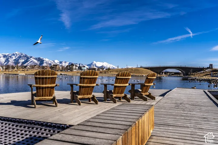 Wood-plank dock featuring built-in wooden bench seating, overlooking a lake with a mountain backdrop