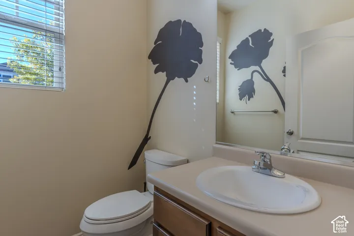 Bathroom featuring a wood-finish vanity with a drop-in sink, solid-surface countertop, chrome faucet hardware, and a wall-mounted mirror