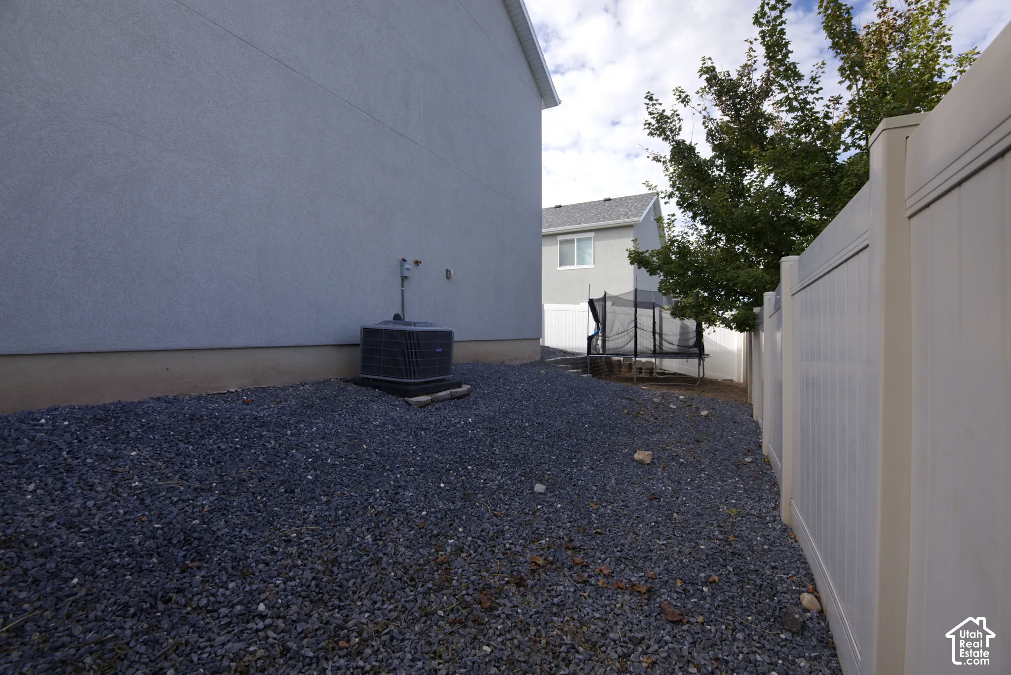Side yard featuring decorative gravel ground cover and white vinyl privacy fencing
