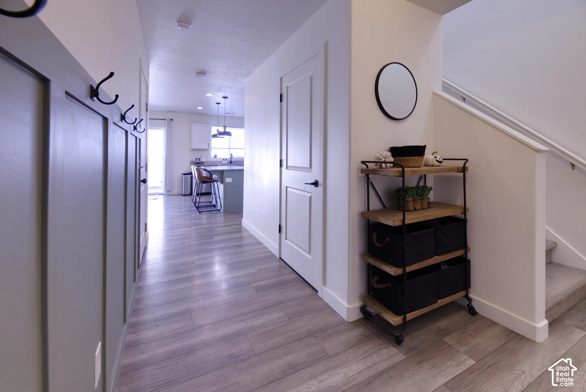 Entryway featuring gray board-and-batten wall detailing with mounted hardware, wood-finish flooring, two-panel interior doors, and a staircase with a handrail